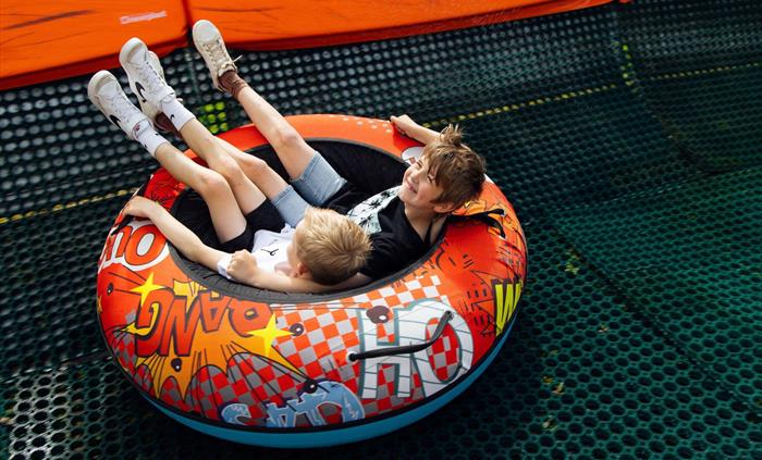 Two young boys sat in the round tube smiling.